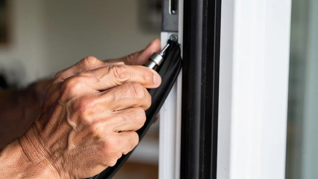 Mains d'un vitrier professionnel installant un nouveau joint d'étanchéité sur le cadre d'une fenêtre